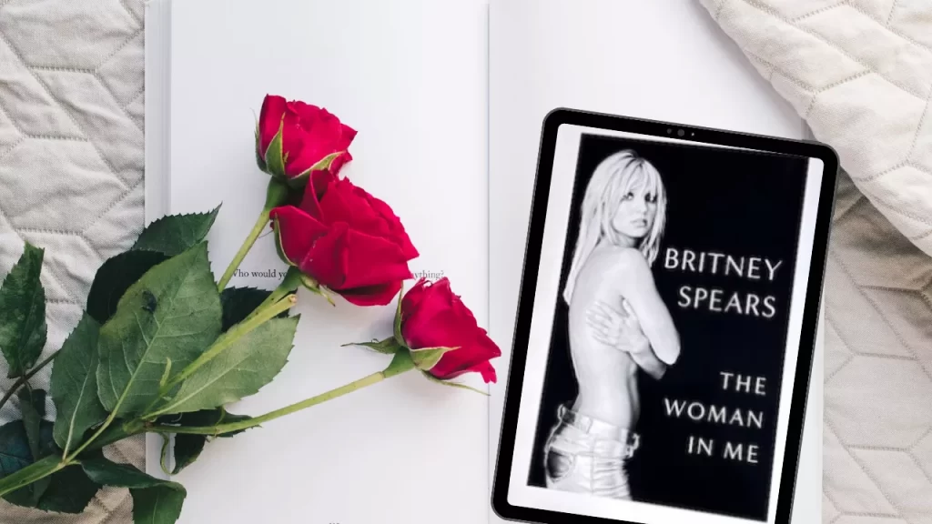The Woman in me livro aberto ao lado de rosas vermelhas simbolizando autocuidado e autoestima juntamente com um tablet com a capa do livro de Britney Spears