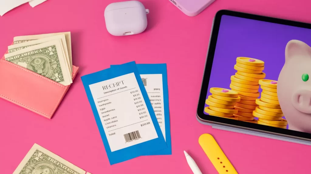 Tablet com imagem de moeda e cofre de porco simbolismo de como economizar dinheiro, relógio ao lado, cupons de despesas para mensurar gastos desnecessários.