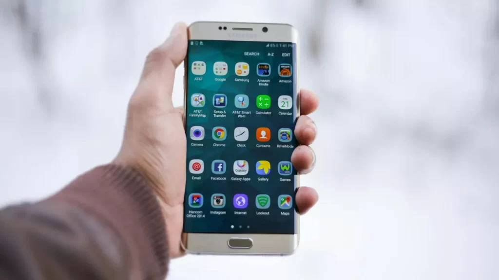 Pessoa segurando um smartphone com a tela mostrando vários apps baixados, muitas vezes sem uso.